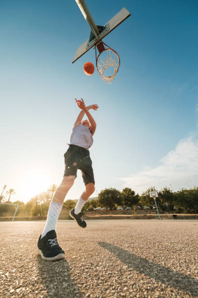 istock Boy throwing ball in hoop with hands raised 1591662742