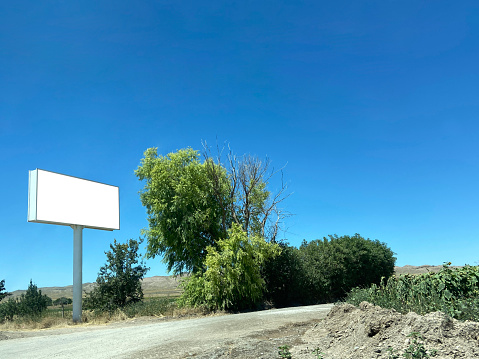 Empty billboard on country road with nature and clear sky background (Frame with clipping path)