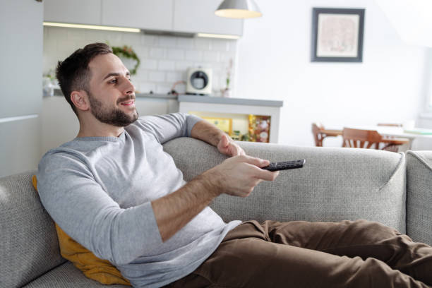 istock Young man watching TV at home 1591669930