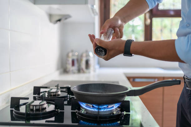 Man Putting Salt In Frying Pan