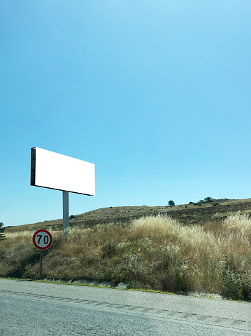 Empty billboard on the roadside with nature and clear sky background (Frame with clipping path)