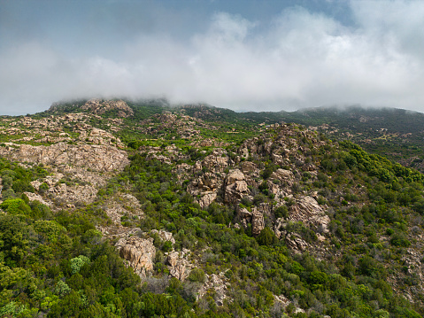 Landscape in Gallura, with granite rocks and mountain in background, fog or low clouds