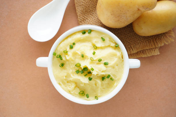 istock Mashed potatoes in bowl and fresh potatoes on wooden table. Clos 1591705019