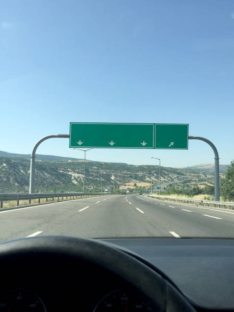 istock Driving car on highway with empty traffic directional sign 1591705025