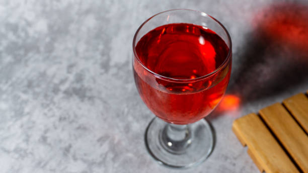 sirop rouge aromatisé à la framboise dans une tasse en verre isolée sur fond gris - editorial label man made material healthcare and medicine photos et images de collection