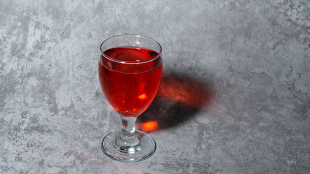 sirop rouge aromatisé à la framboise dans une tasse en verre isolée sur fond gris - editorial label man made material healthcare and medicine photos et images de collection