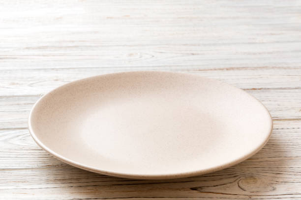istock Perspective view of empty light plate on wooden background. Empty space for your design 1591716048