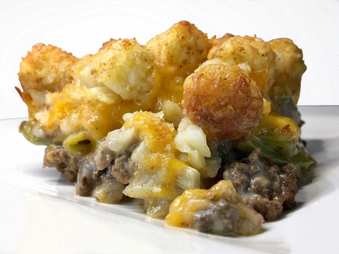 Ah, the Midwestern Tater Tot Hotdish. A true comfort food, steeped in the rich culinary traditions of the heartland. Picture, if you will, a casserole dish, brimming with layers of warmth and nostalgia.

At its core, the Tater Tot Hotdish is a harmonious union of hearty ingredients, brought together to create a symphony of flavors. Ground beef, seasoned to perfection, becomes the sturdy foundation of this dish. Browned to a golden hue, it exudes an enticing aroma that beckons even the most discerning palate.

Next, the stage is set for fork tender green beans. Their freshness and sweetness fuse effortlessly with the savory meat, creating a delicate balance that dances on the taste buds.

But it is the crowning glory of this dish that truly captivates — the irresistible blanket of crispy Tater Tots. Like a patchwork quilt adorning the casserole, these golden nuggets offer a delightful crunch that contrasts with the tender layers beneath. Baked to perfection, they provide not only a visual feast, but a texture that elevates the entire dish to new heights.

Please, imagine the aroma wafting through the air as it emerges golden and bubbling from the oven. The melding of ingredients, the harmonious symphony of flavors, all culminate in a dish that is both comforting and indulgent. A warm embrace on a chilly Midwestern evening.

As your fork dives into the layers, relish in the joy of this quintessential Midwestern creation. Allow the flavors to transport you to a simpler time, where family and community sit around a cozy table, sharing stories and laughter.

So, dear friend, seek out the Midwestern Tater Tot Hotdish and embark on a culinary journey through the heartland. Experience the true essence of the Midwest, served one delicious bite at a time.