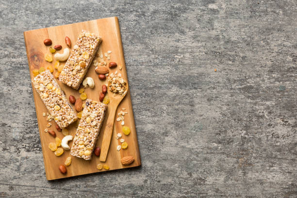 varias barras de granola sobre el fondo de la mesa. barras de granola de cereales. barritas de desayuno de superalimentos con avena, nueces y bayas, de cerca. concepto de superalimento - protein bar cereal oat cranberry fotografías e imágenes de stock