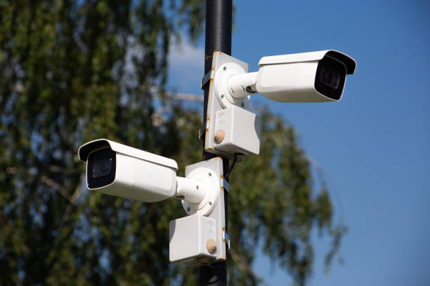 istock Two white surveillance cameras on a pole look in different directions 1591718428