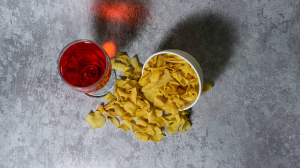 sirop rouge aromatisé à la framboise dans une tasse en verre et chips de manioc dans un bol en plastique blanc isolé sur fond gris - editorial label man made material healthcare and medicine photos et images de collection