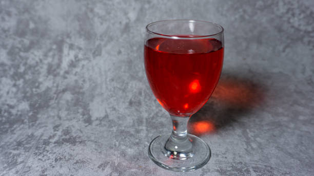 sirop rouge aromatisé à la framboise dans une tasse en verre isolée sur fond gris - editorial label man made material healthcare and medicine photos et images de collection