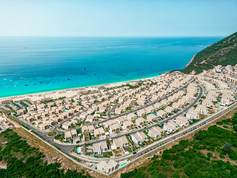 Gorgeous private villas with orange roofs and ocean views next to the beach in Albania. Aerial top down view of luxury oceanfront green coast pool villas. Comfortable rest and privacy.