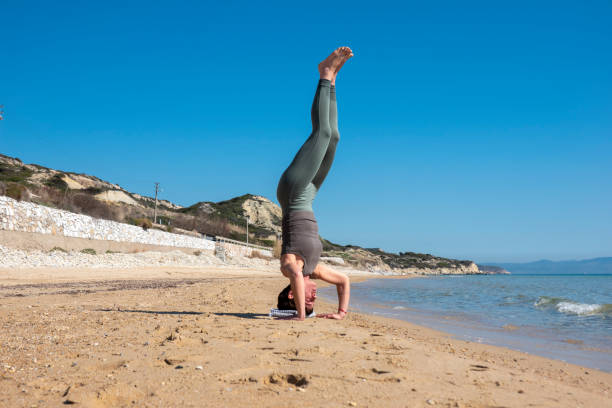 istock Attractive middle-aged woman practicing yoga on a beautiful beach 1591737996