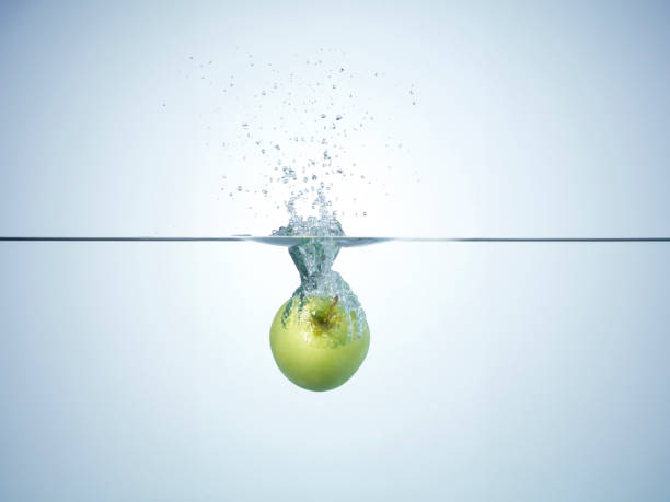 Fresh apple dropped in water. Apple splashing a lot of water droplets and bubbles you enter the water.