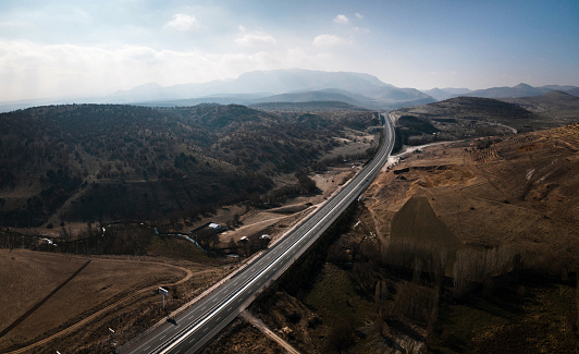 Highway going though fields and mountains. Aerial drone view of multi-lane road