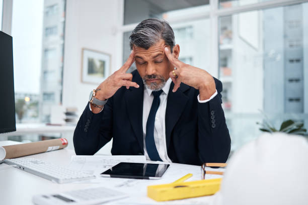 istock Stress, tired and architect man in an office with a design problem, mistake or deadline for project. Mature male engineer frustrated with headache, fatigue or crisis in construction industry 1591798810