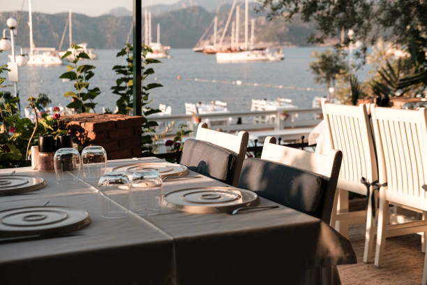 istock served table in coast seaside restaurant, white and blue colors, sunset time, dinner at seaview with sailing boats at anchor 1591802606