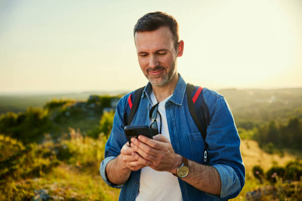 istock Portrait of handsome male backpacker using his smartphone while hiking 1591804816