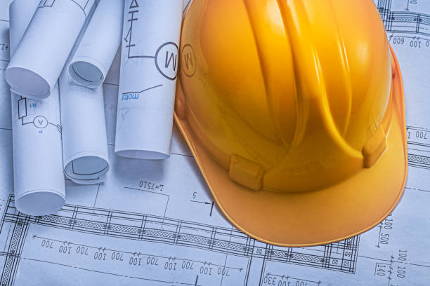 istock An Yellow Construction Helmet On Background Of Blueprints. 1591809716