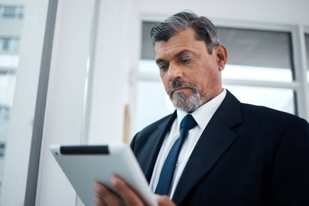 istock Business, app or senior man with a tablet, online reading or connection with network, email or digital information. Consultant, employee or entrepreneur with technology, schedule planning on calendar 1591813238