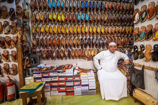 Al-Balad, Jeddah, Saudi Arabia - March 16th 2023: In the heart of the old town Al-Balad you can find original and traditional stores on every corner. Here a salesman proudly presents himself in a typical, very small shoe store.