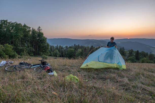 istock Man camping in summer sets up a tent at sunset 1591890931