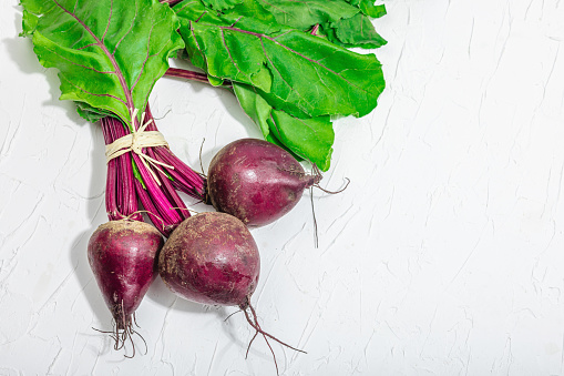 Fresh crop of beetroots, healthy ingredient for cooking food. Trendy hard light, dark shadow, white plaster background, flat lay, top view