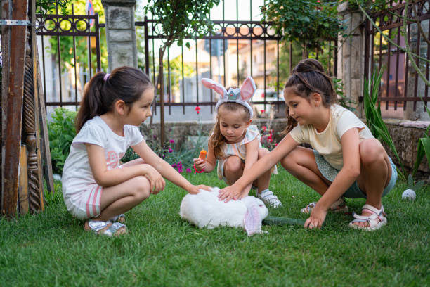 istock Sisters petting and feeding rabbit with cucumber and carrot, during an Easter celebration 1591896976