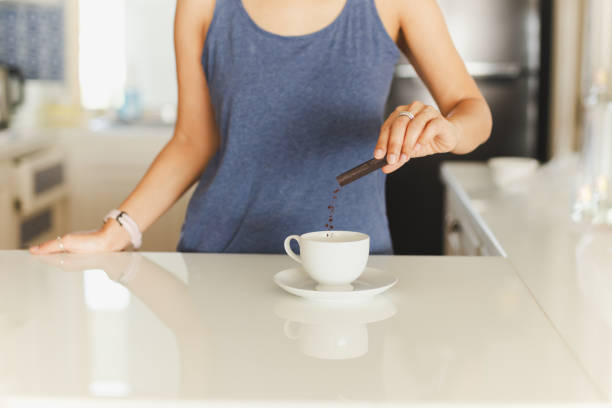 Woman hand pouring instant coffee sachet into a cup