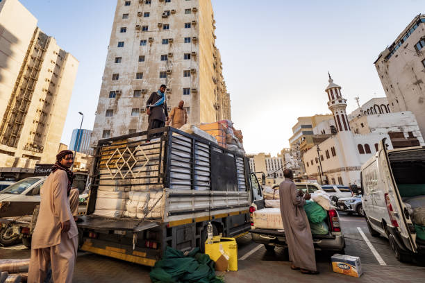 View of local men loading purchased bales of textile goods onto a truck, next to the souk in Al-Balad, Jeddah, KSA, Saudi Arabia Al-Balad, Jeddah, Saudi Arabia - March 16th 2023: Outside the imaginary border of Al-Balad, men load a truck and a pick-up truck with rolls of fabric they have just bought in one of the many textile and fabric stores in Al-Balad. curbsidepickup stock pictures, royalty-free photos & images