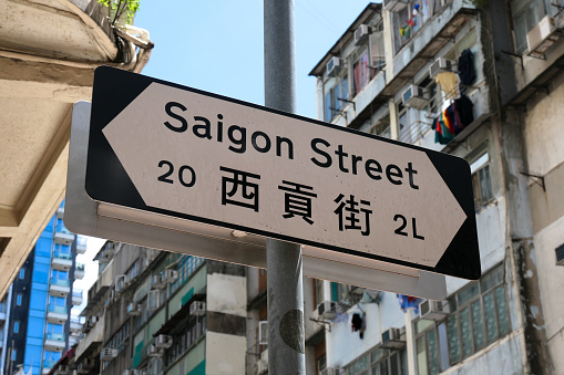 Saigon Road street sign near the corner of Nathan Road, Kowloon. In the background are residential buildings.  This image was taken on a sunny afternoon on 6 July 2023.