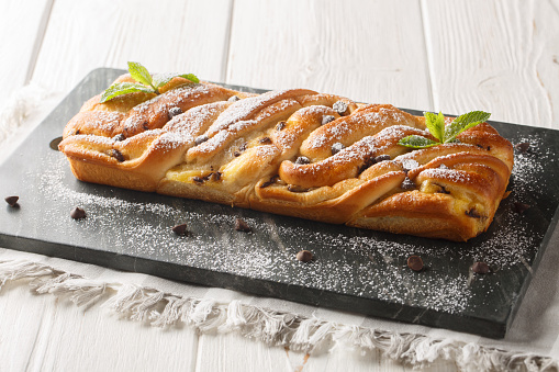 Dessert festive braided sweet bread with chocolate and custard close-up on a slate board on the table. Horizontal