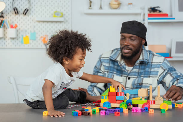 istock Black father watching his children Play jigsaw puzzles, A boy playing plastic jigsaw puzzles to promote age-related development, learning skills with learning materials to develop children's learning. 1591947542