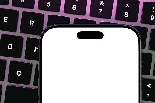 Smartphone showing a blank white screen on top of a silver laptop illuminated by purple light. Illustration as design element for technical topics
