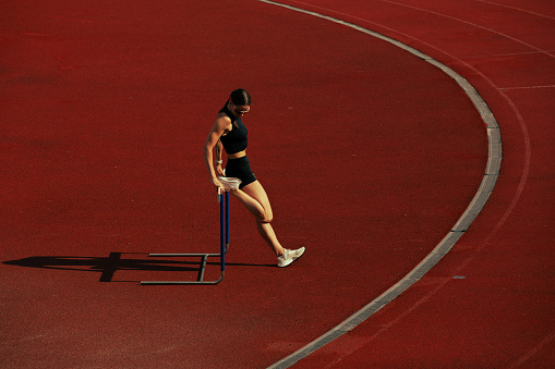 Female athlete training high jump over a four metre long horizontal bar. Sport and endurance concept.