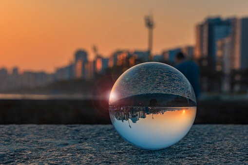 City of Santos, Brazil. Glass ball with focus reflecting the waterfront buildings and the beach at sunset with blue sky. Selective focus with blurred background.