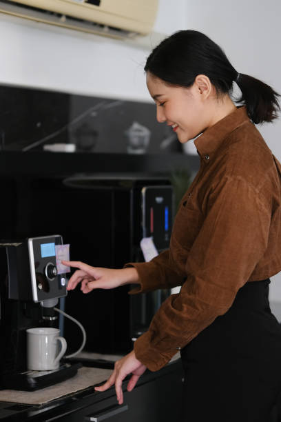 istock Asian business woman using coffee machine in the office. 1592012278
