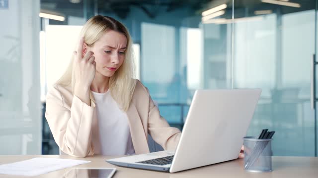 Frustrated businesswoman complains about poor performance of computer program on laptop while sitting in office