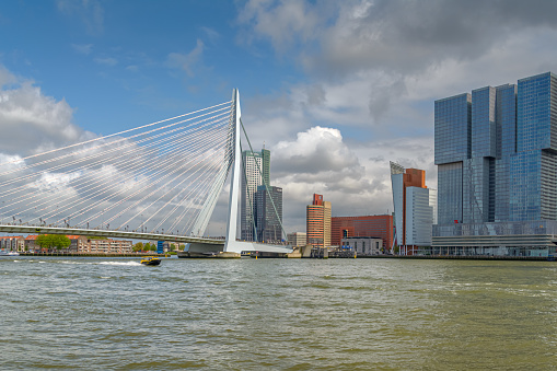 Rotterdam, The Netherlands- May 14, 2016: The Kop van Zuid in Rotterdam on a summer day. A boat from Port of Rotterdam sails over the Maas