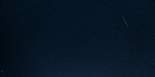 Natural Night Starry Sky. Glowing Stars And Meteoric Tracks Trail In Dark Night Starry Sky Background. Glowing Stars And Meteorite Trails.