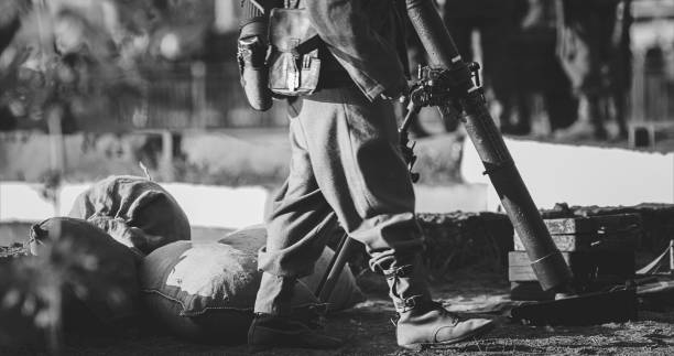 vista de primer plano de un recreador vestido como soldado de infantería alemán de la wehrmacht en la segunda guerra mundial con ametralladora mp 40 patrulla territorio de la tripulación de mortero. soldado alemán guarda mortero. blanco y negro - gun turret fotografías e imágenes de stock