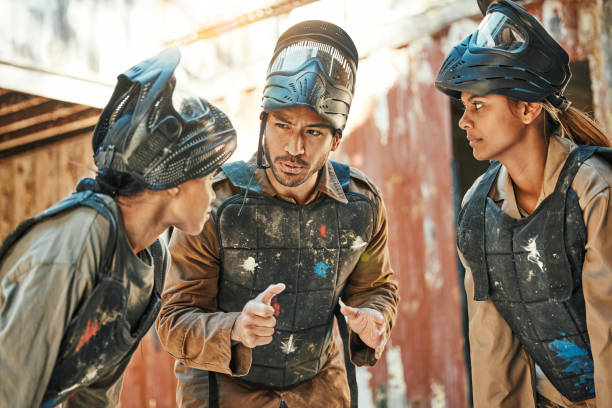 istock Paintball game, team strategy and man explain ideas, training challenge or battlefield conversation, plan or tactical survival. War mission, friends group and talking people listen to battle planning 1592049279
