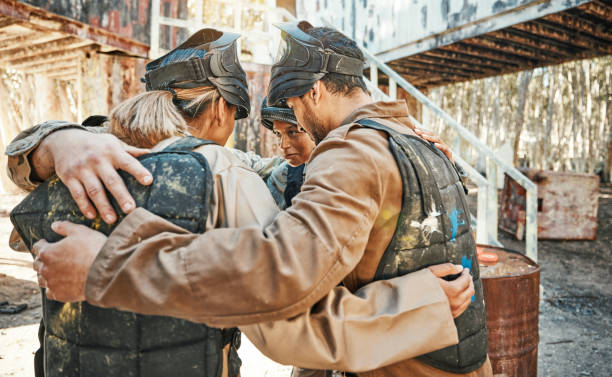 istock Paintball game, group huddle and team support, discussion and talk about training challenge, battlefield collaboration or survival. War mission, friends circle and people listening to battle tactics 1592049295