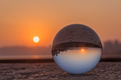 City of Santos, Brazil. Glass ball with focus reflecting the waterfront buildings and the beach at sunset with blue sky. Selective focus with blurred background.
