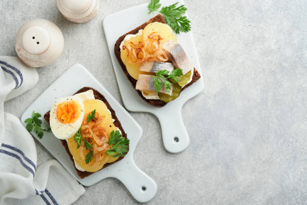 istock Open sandwich or smorrebrod with rye bread, herring, eggs, caramelized onions, parsley and cottage cheese on old wooden rustic table backgrounds. Danish or Scandinavian traditional food snack lunch. 1592068826