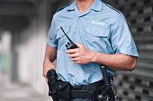 Security guard, safety officer and man with walkie talkie in hand on street for protection, patrol or watch. Law enforcement, focus and duty with a crime prevention male worker in uniform in the city