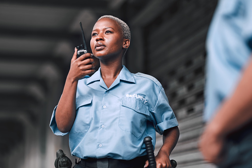 Police, communication and black woman law enforcement worker talking on walkie talkie or radio for emergency. Security, legal and officer or employee doing criminal investigation for justice