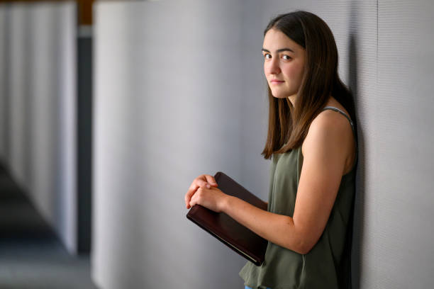 istock Young woman with folder standing in a corridor 1592117808