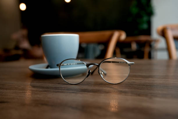 istock Blue coffee cup with spectacles on a wooden table 1592128016